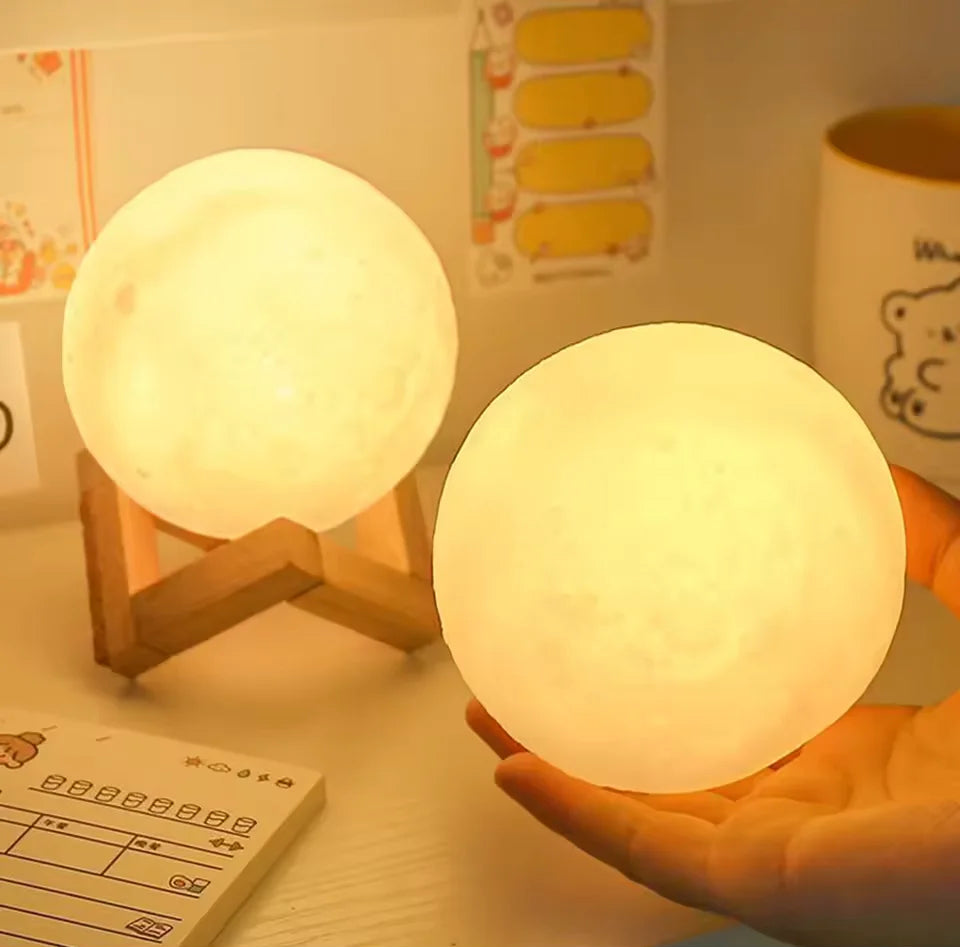 Duas luminárias lua com luz amarela sendo apresentadas com a mão