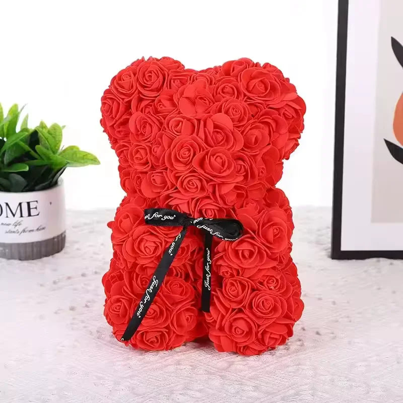 Ursinho vermelho de rosas com laço preto ao lado de planta decorativa