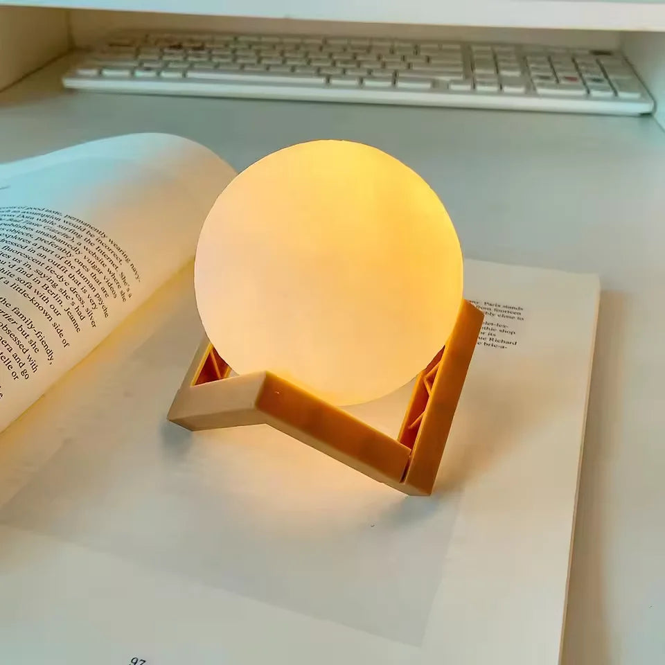 Luminária lua LED acesa decorando mesa branca de quarto